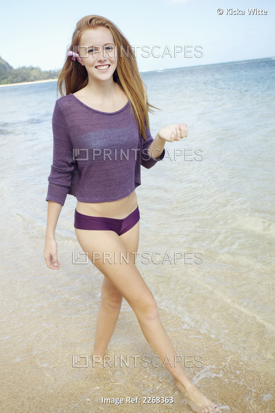 A young woman walks in the shallow water along a beach; Kauai hawaii united ...