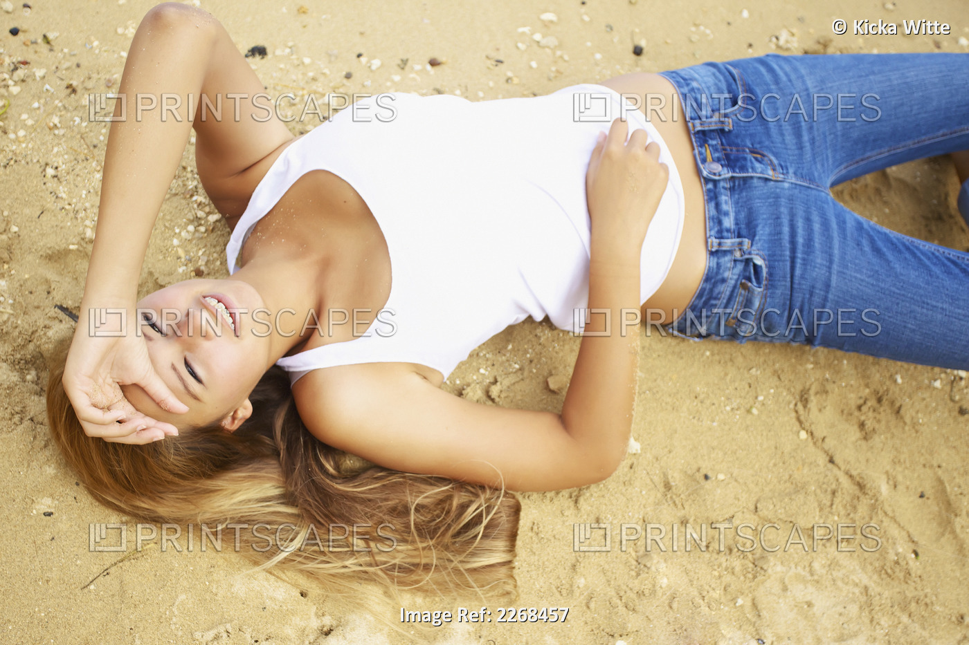 Portrait of a young woman laying on the sand; Kauai hawaii united states of ...