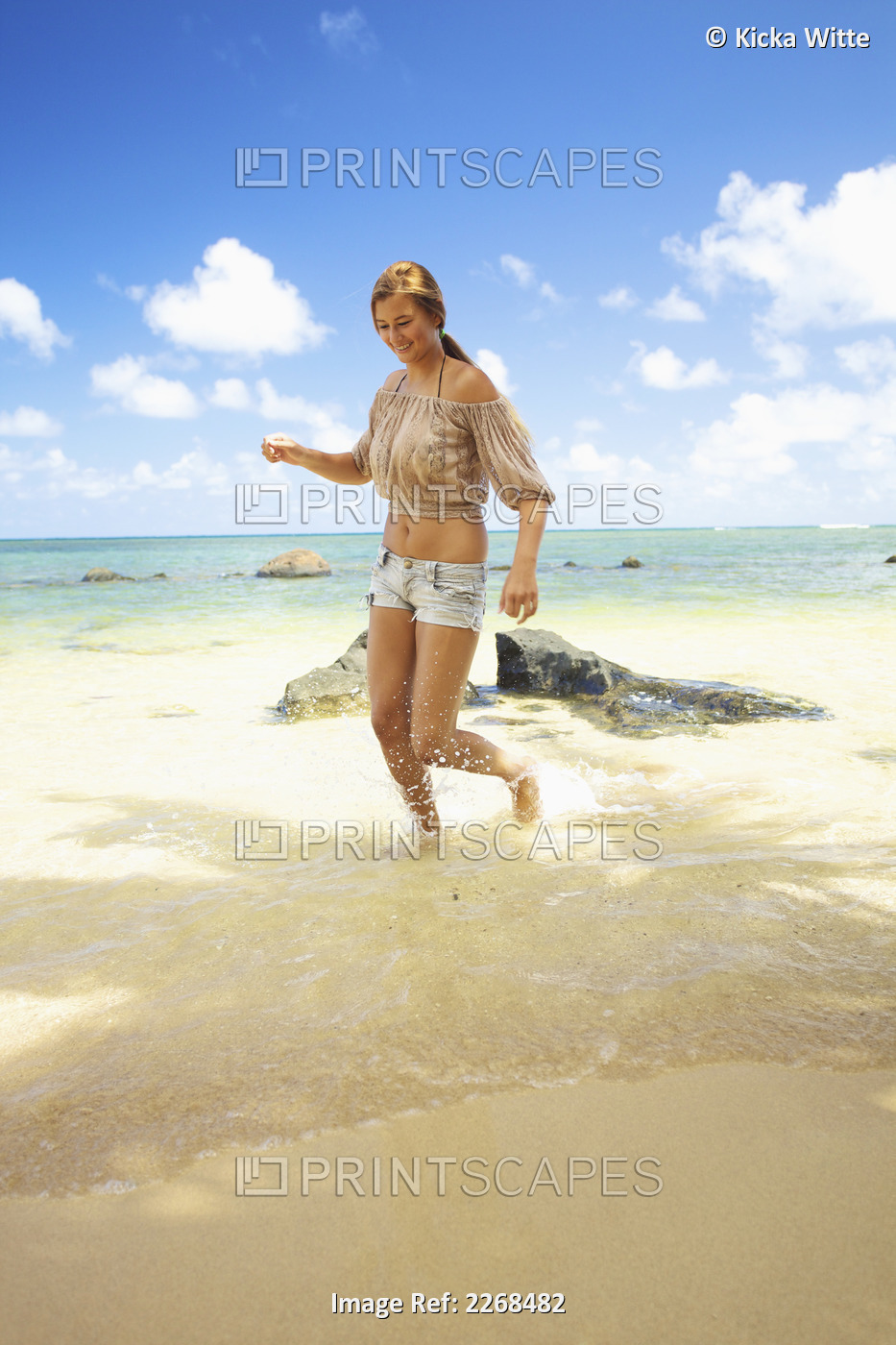 A young woman runs in the shallow water on anini beach; Kauai hawaii united ...