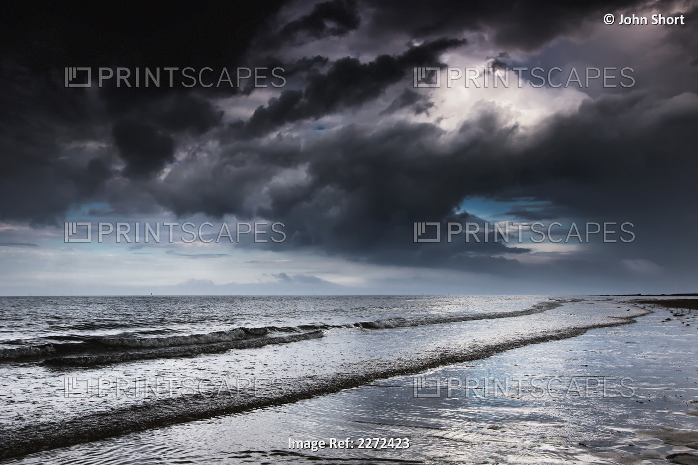 Dark storm clouds over the ocean with waves rolling into the shore;Druridge bay ...