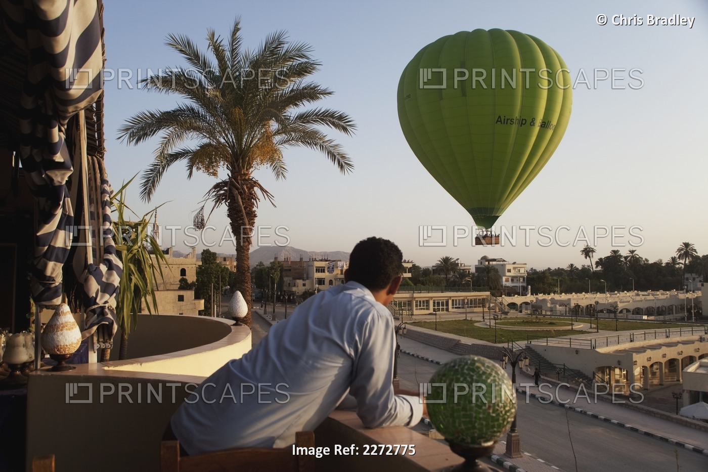 Hotel worker watching hot air balloon from hotel balcony; west bank luxor upper ...