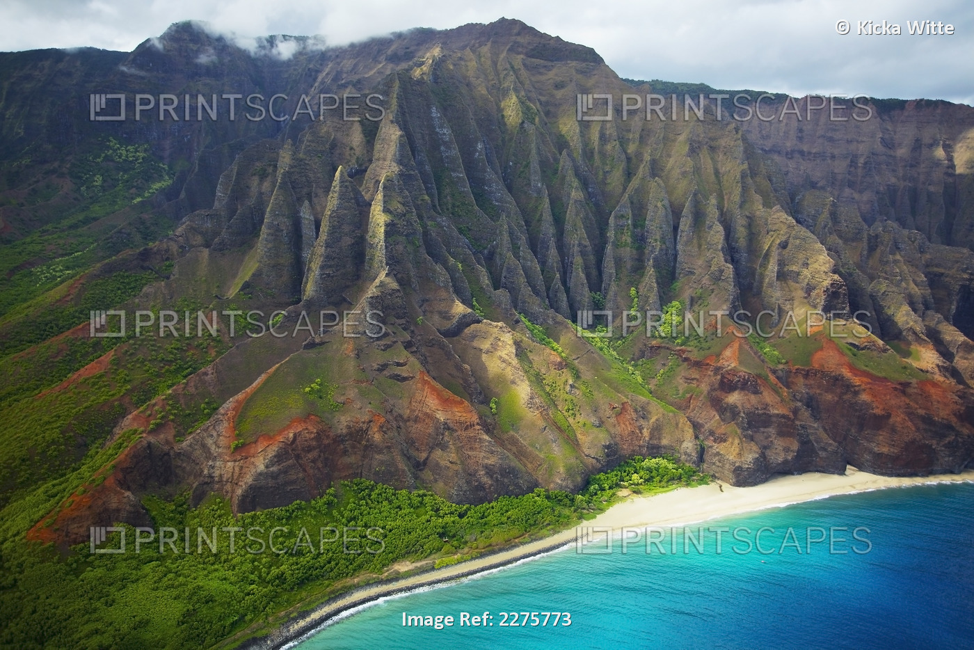 Rugged cliffs and lush foliage with a white sand beach along the coastline of a ...