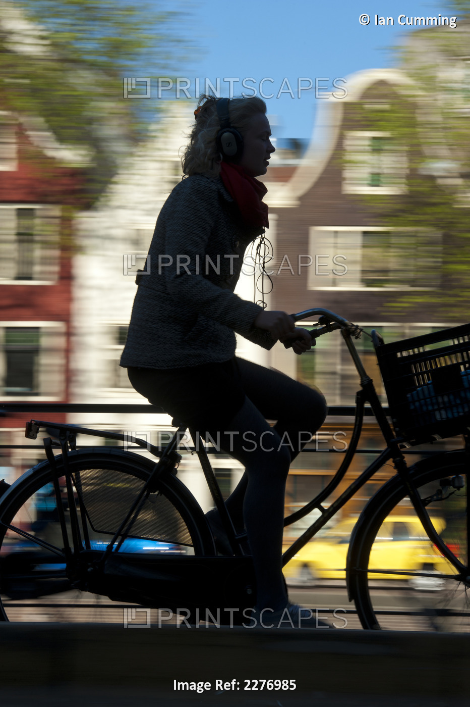 Silhouette Of Cyclist Going Past Canal And Gabled Houses; Amsterdam, Holland