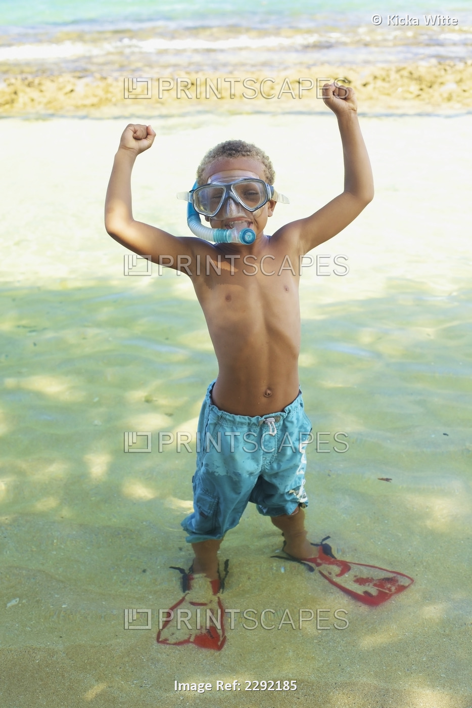 A young boy in the shallow water of the ocean with snorkelling gear; Hawaii ...