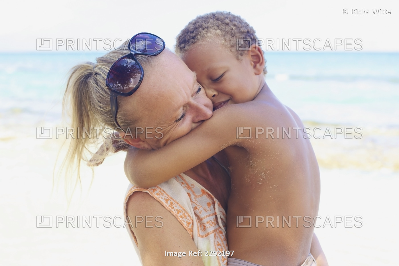 A mother and son in an embrace on the beach at the water's edge; Hawaii united ...