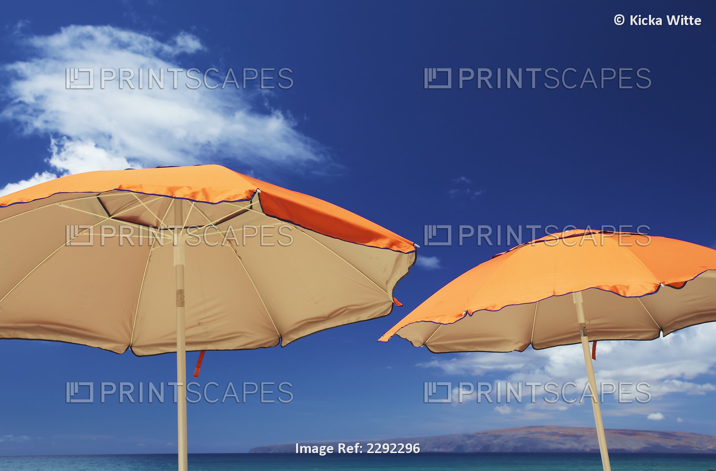 Yellow beach umbrellas against a blue sky with cloud and mountains on the ...