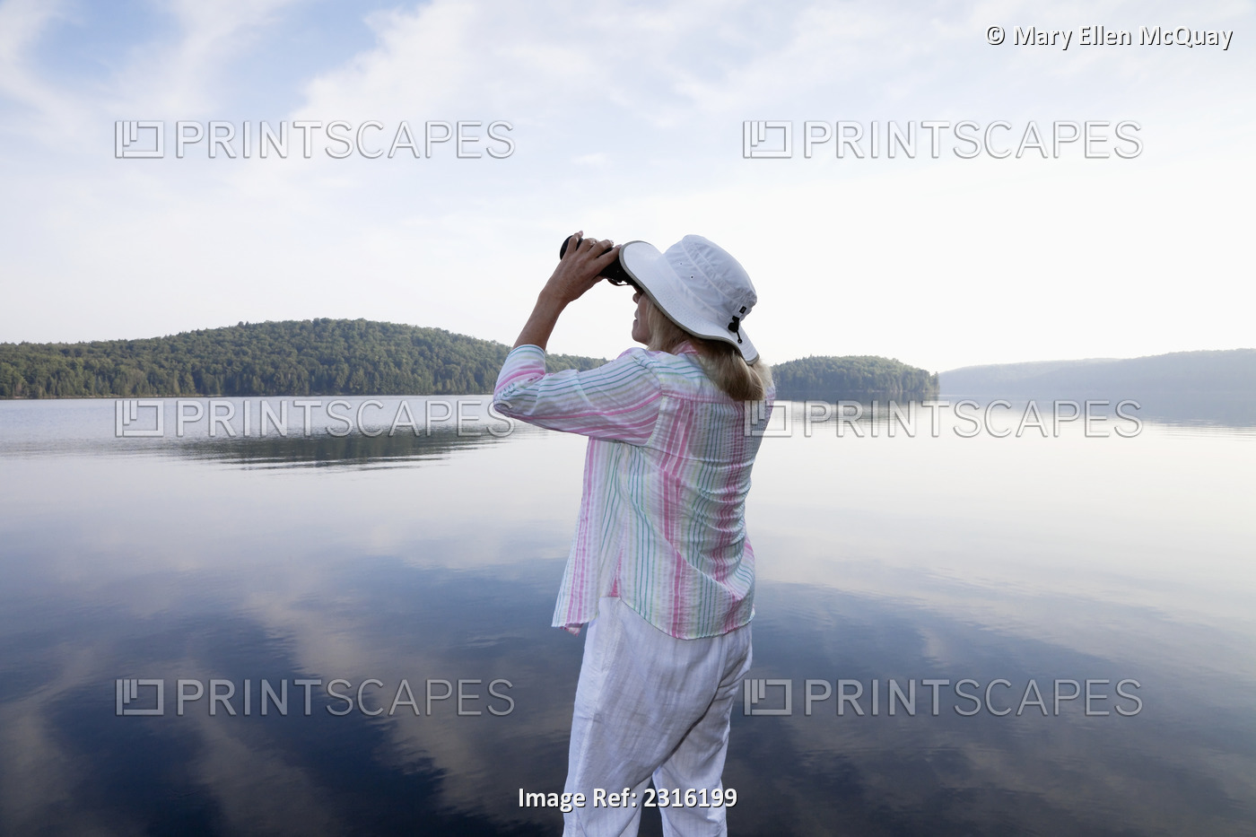 Senior Woman Looking Through Her Binoculars While Standing On Her Cottage Dock ...