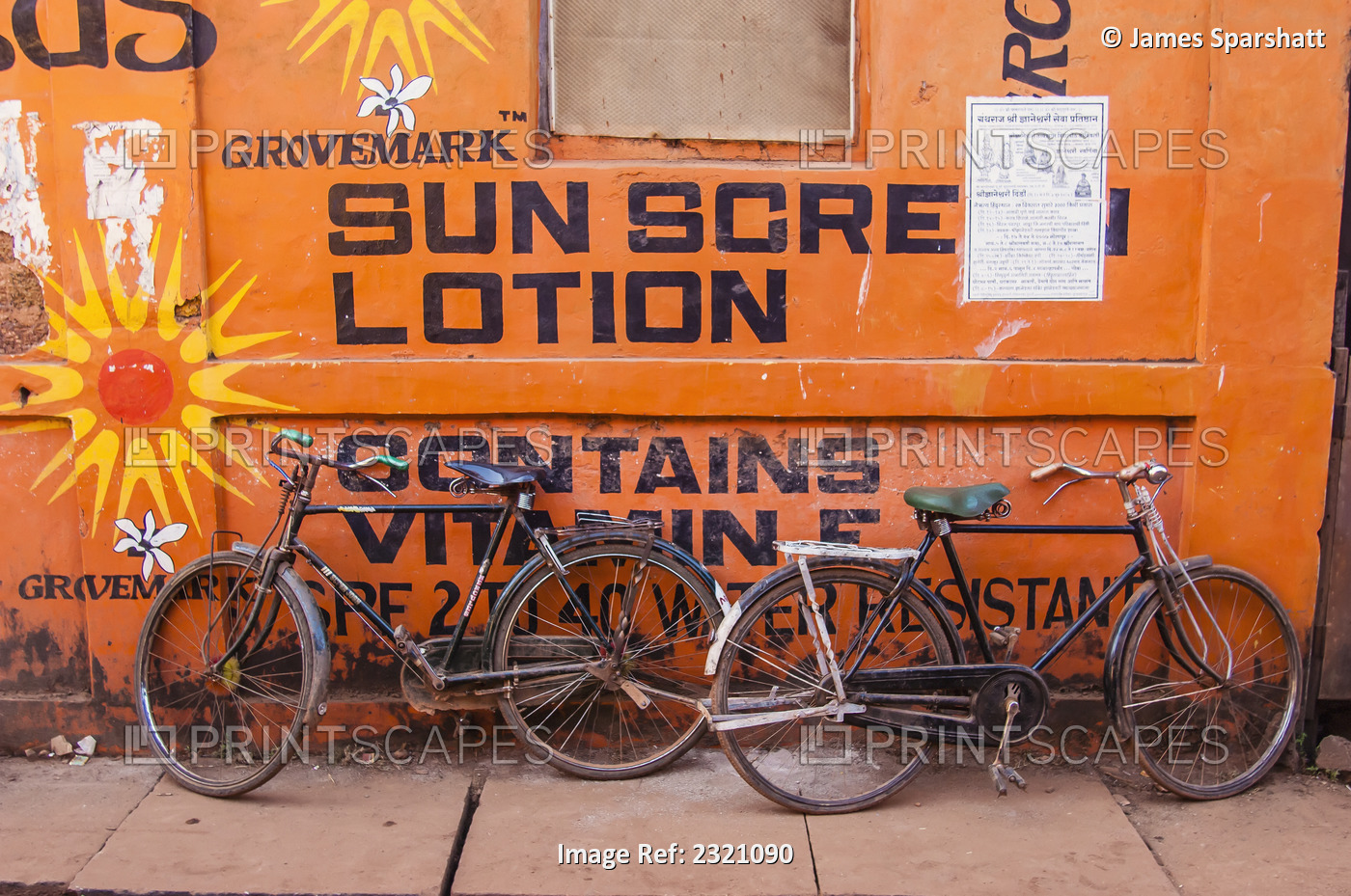 India, Karnataka, Two Bikes Leaning Against Wall Advertising Sun Screen; Gokarna