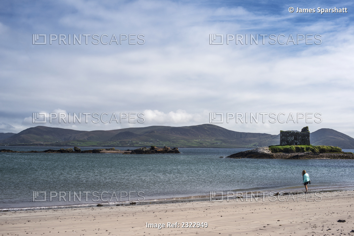 UK, Ireland, County Kerry, Woman walking on beach with Ballinskelligs Castle in ...