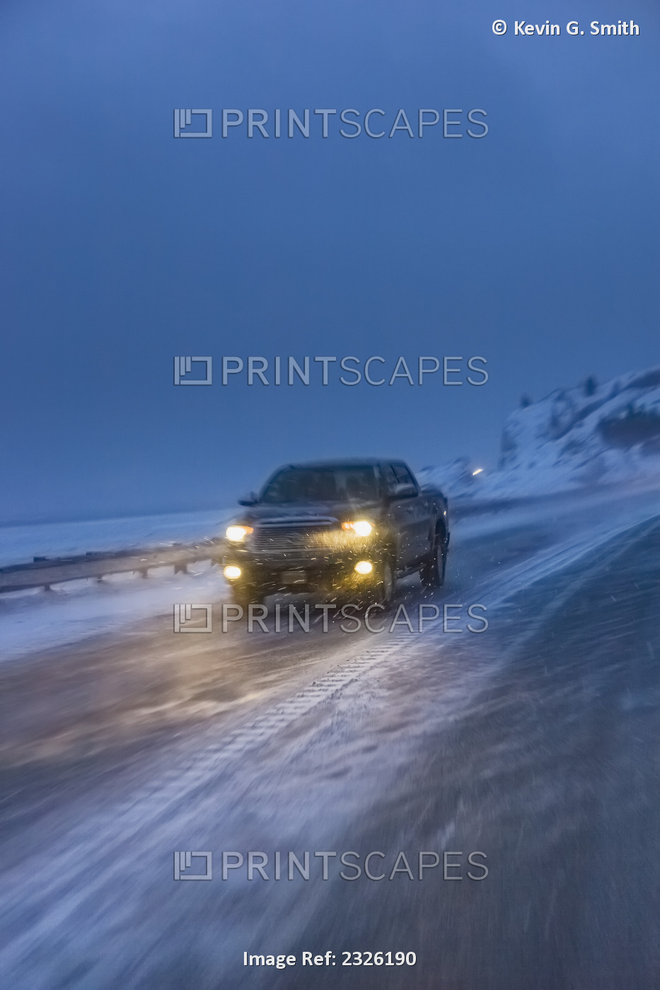 A truck driving on the seward highway during a snowstorm at twilight in winter, ...