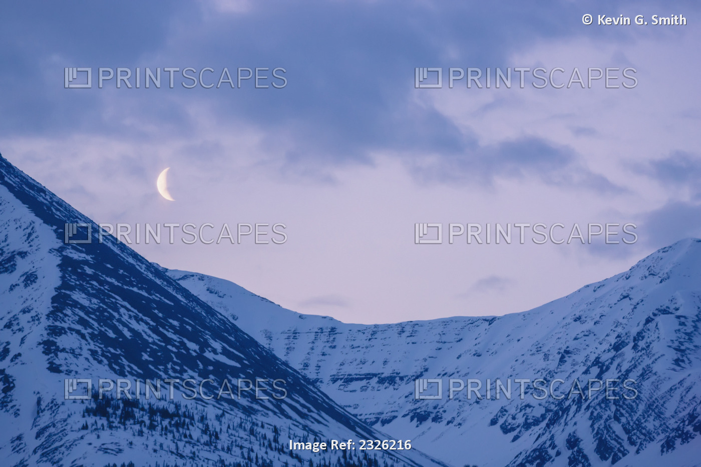 The crescent moon sets above the sentinal range along the alaska highway, ...