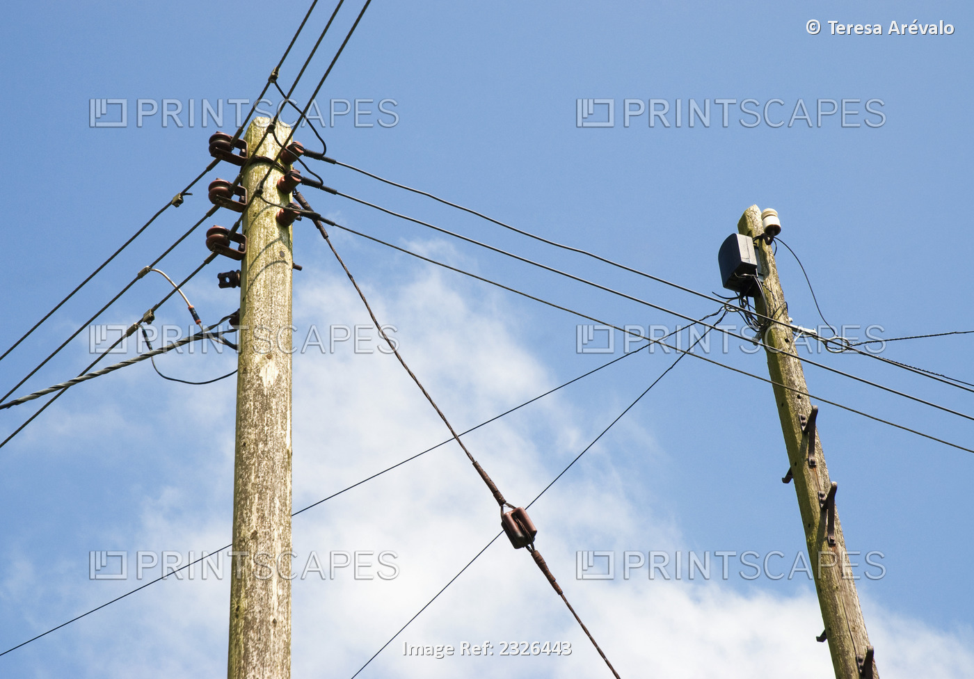 Telephone and electricity cables against a blue sky and cloud; England