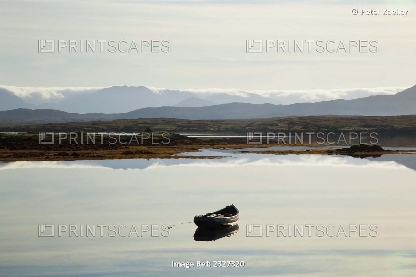 A rowboat sits in a tranquil lake with hills in the background near ...
