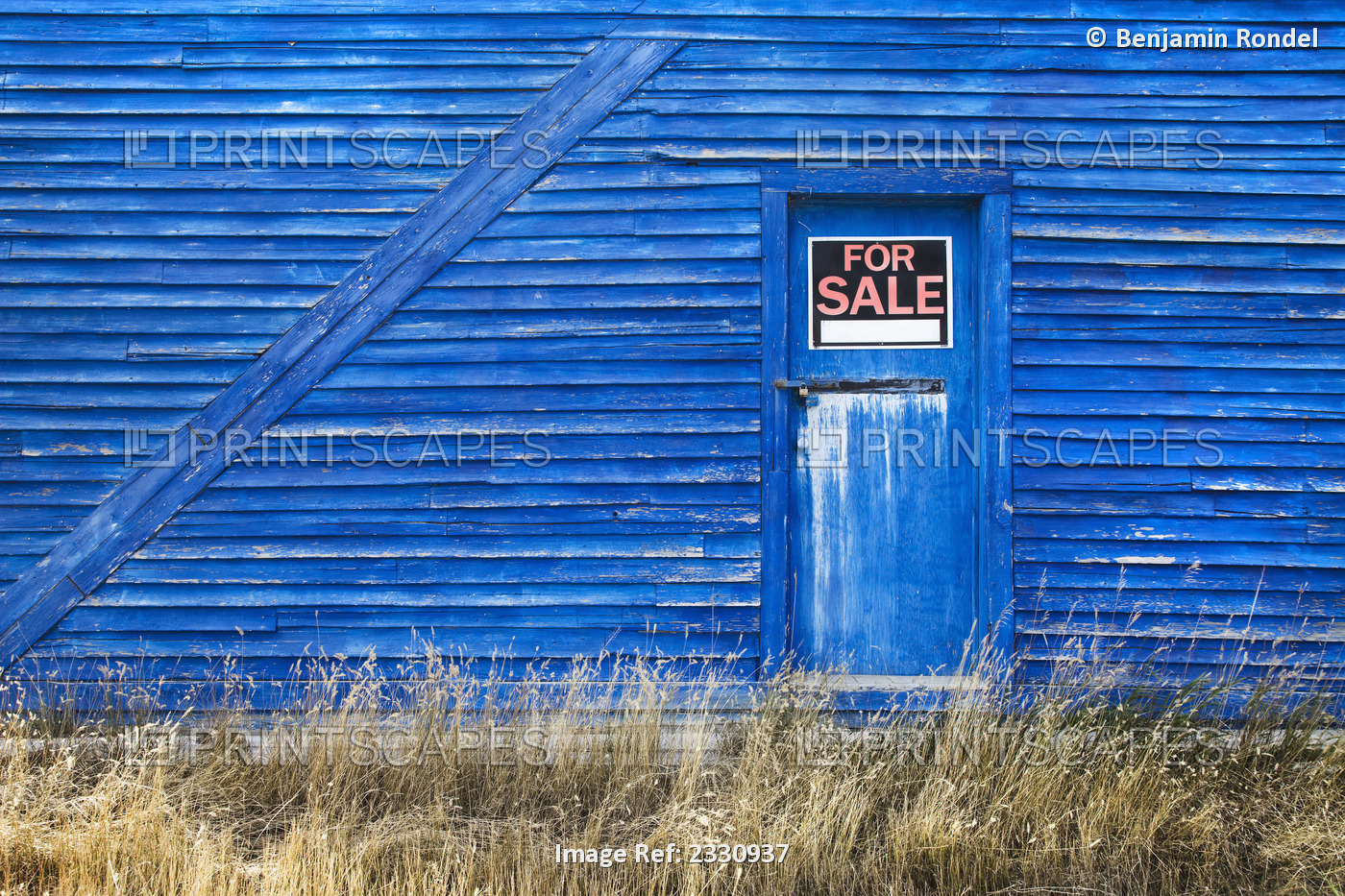 A blue barn with a for sale sign in the window of the door; Saskatchewan canada