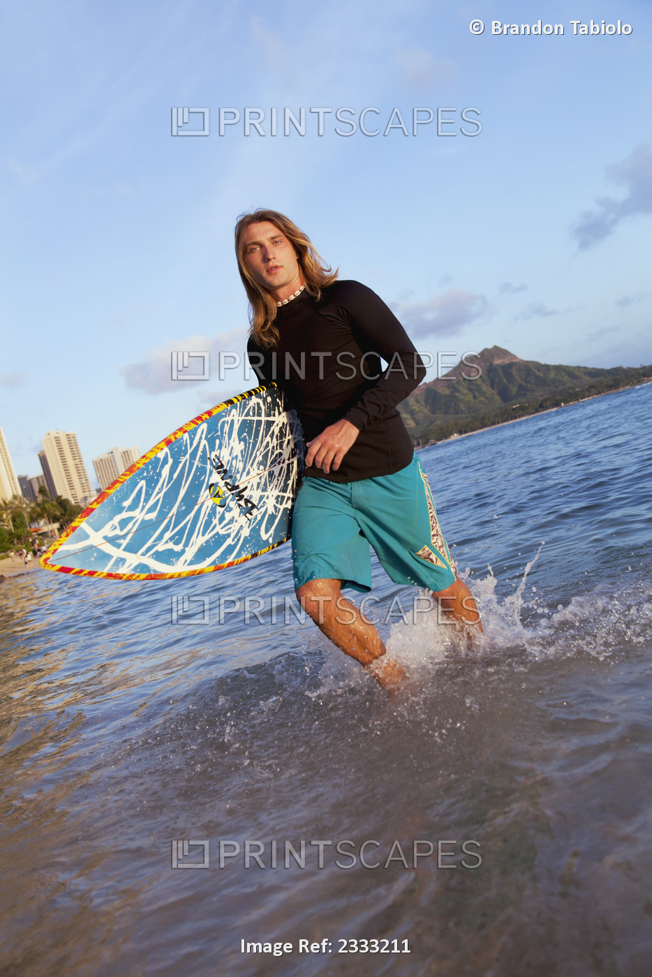 A Surfer Carrying His Surfboard And Walking In Shallow Water; Waikiki, Oahu, ...