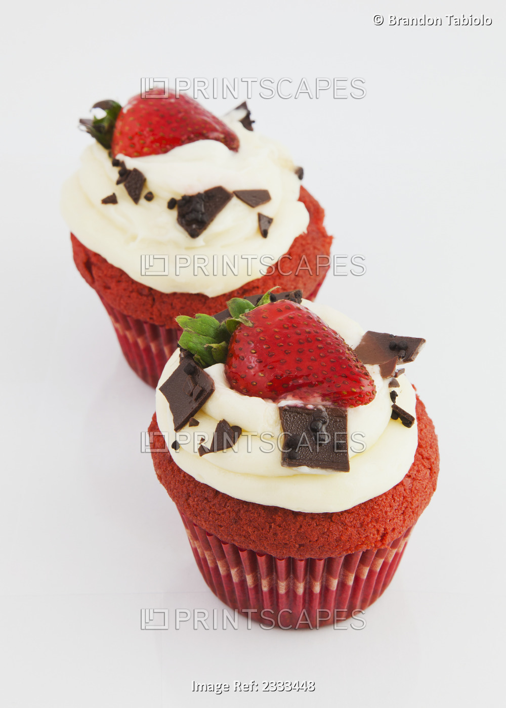 Red velvet cupcakes with icing garnished with chocolate and strawberries on a ...