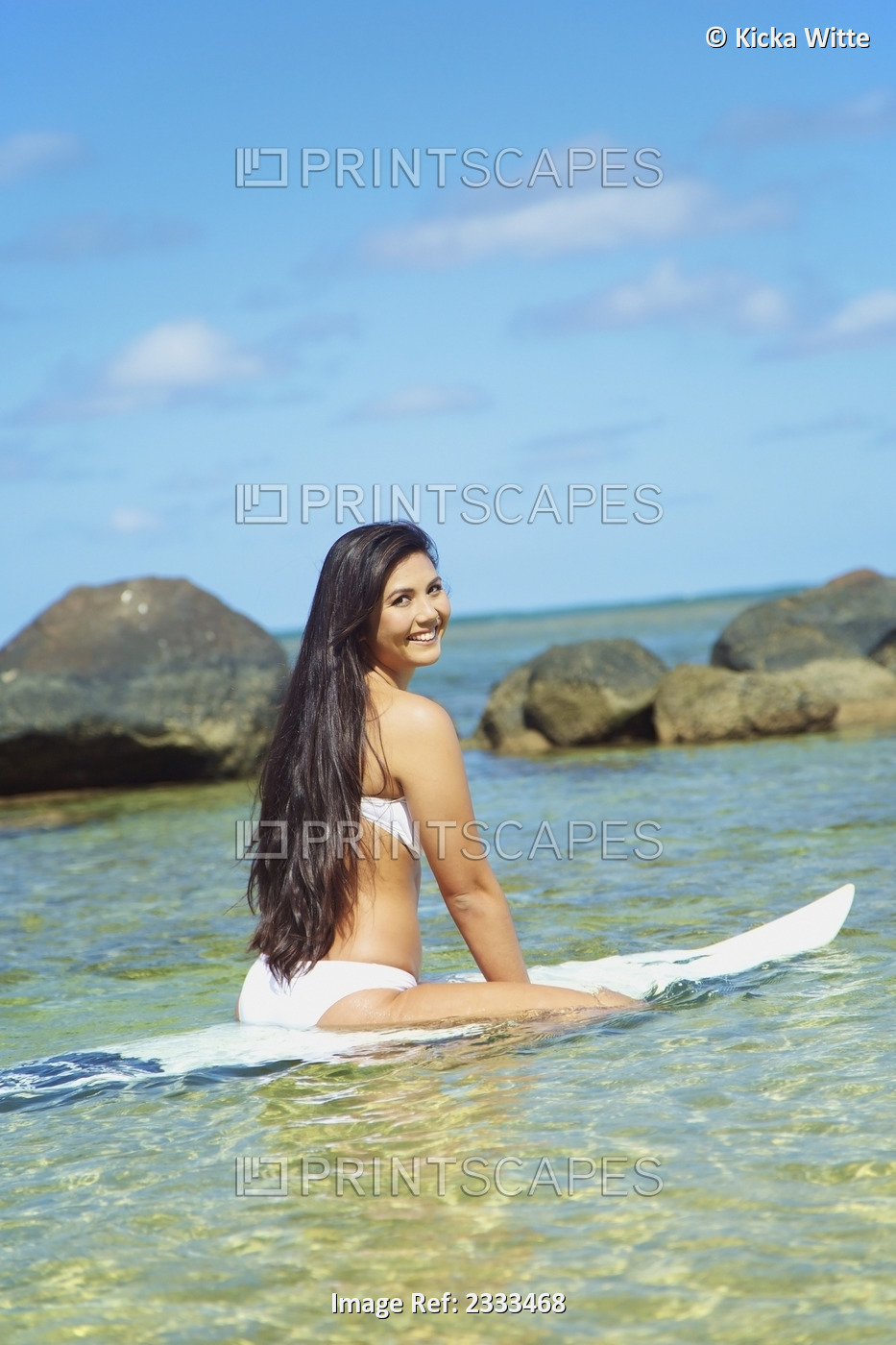 A Young Woman In A Strapless Bikini Sitting On A Surfboard; Kauai, Hawaii, ...