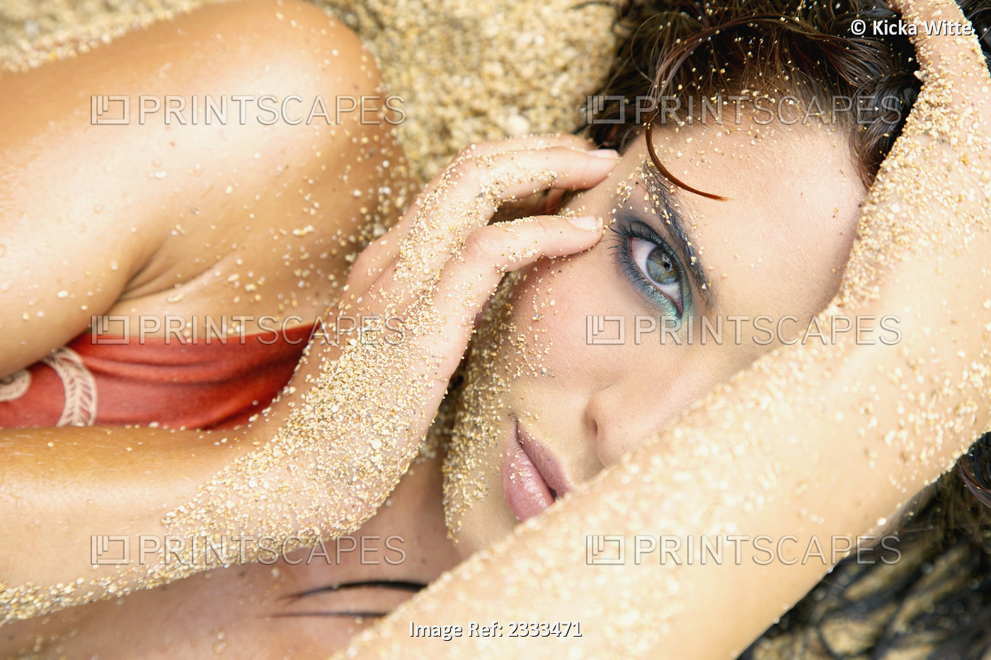 A Woman Laying In The Sand With A Sandy Face, Hair And Arms; Kauai, Hawaii, ...