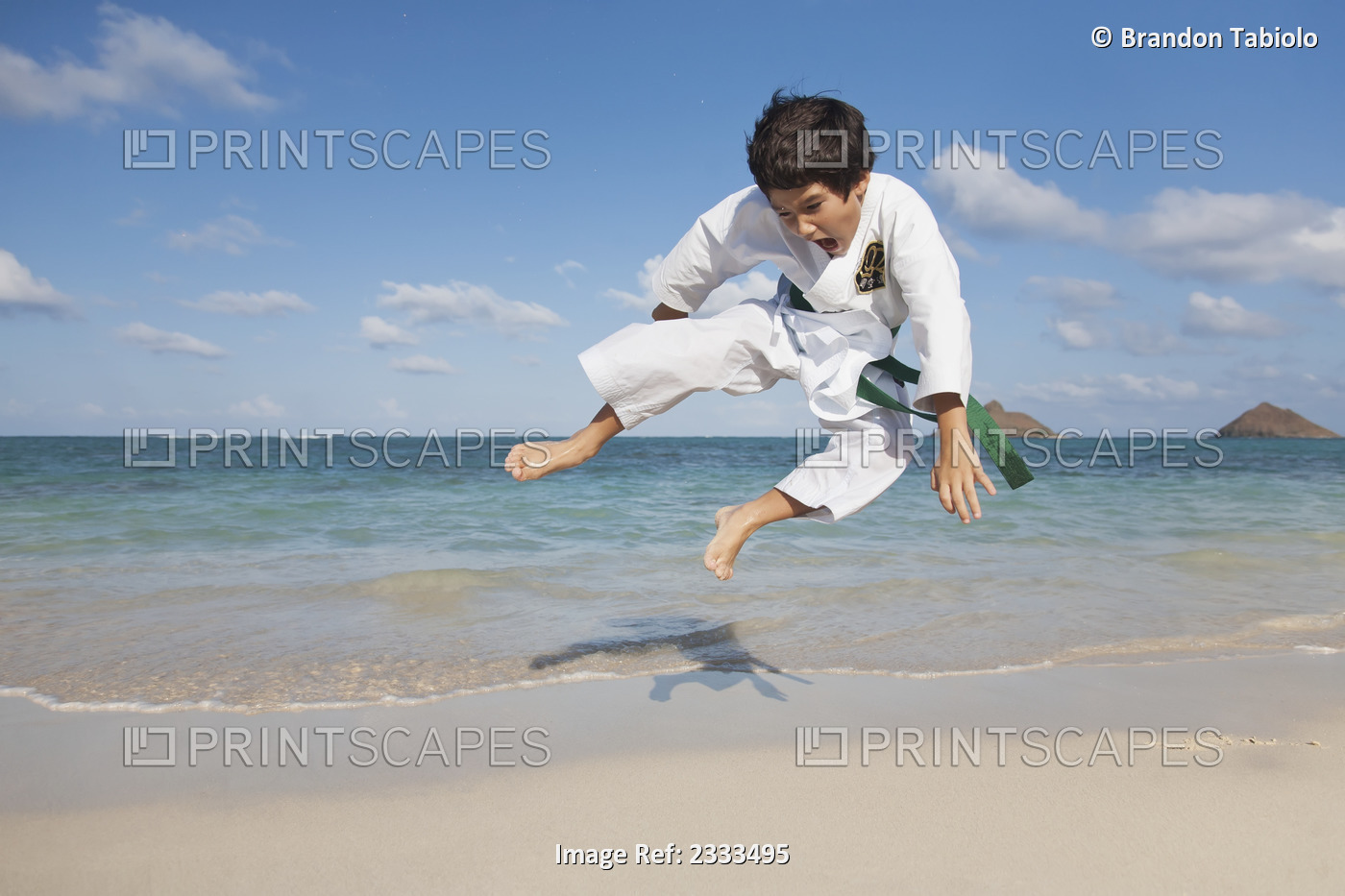 A Boy In A Martial Arts Uniform Leaping On A Beach; Honolulu, Oahu, Hawaii, ...