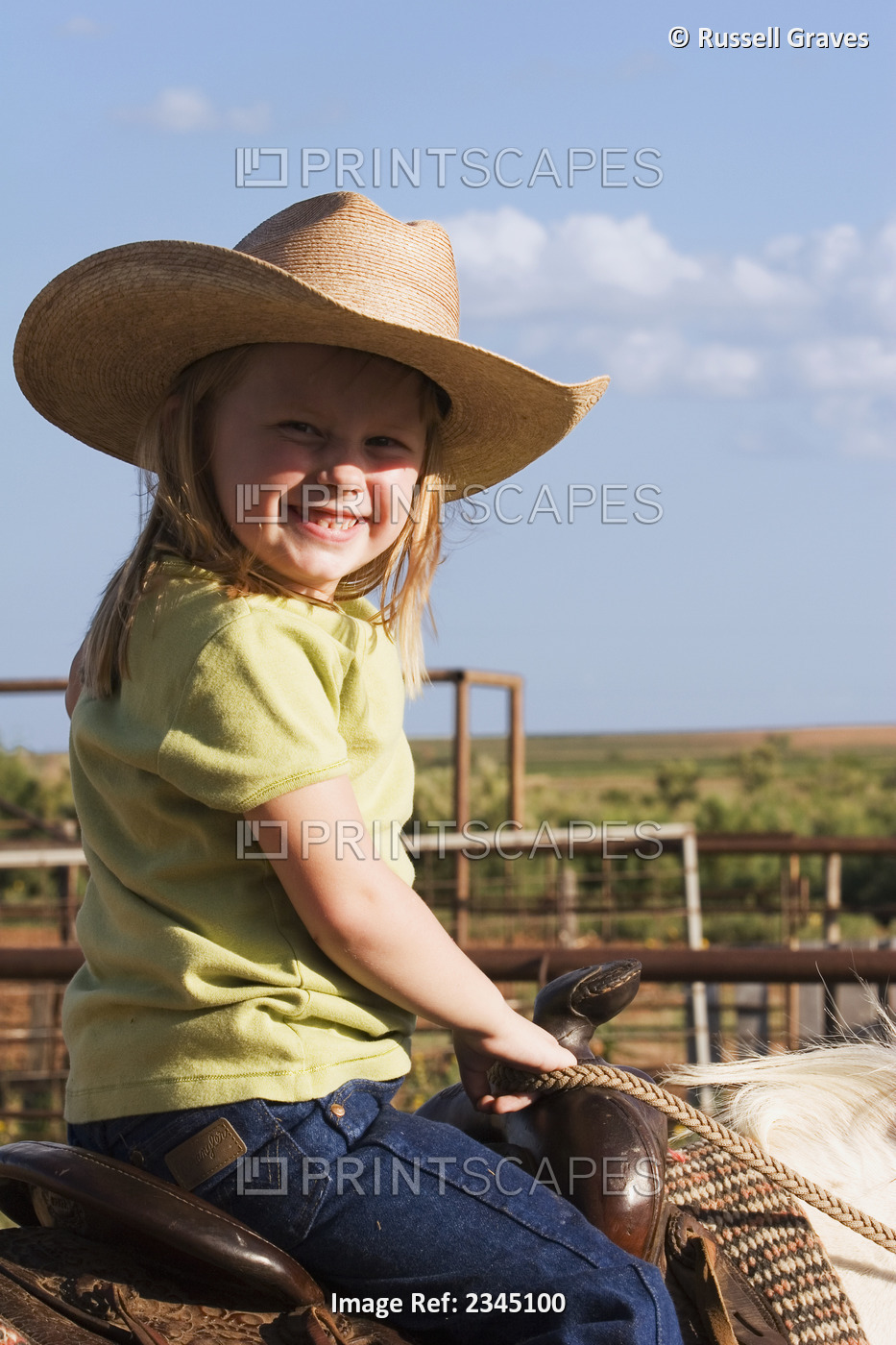 Agriculture - A young cowgirl sitting on a horse smiles at the camera / ...
