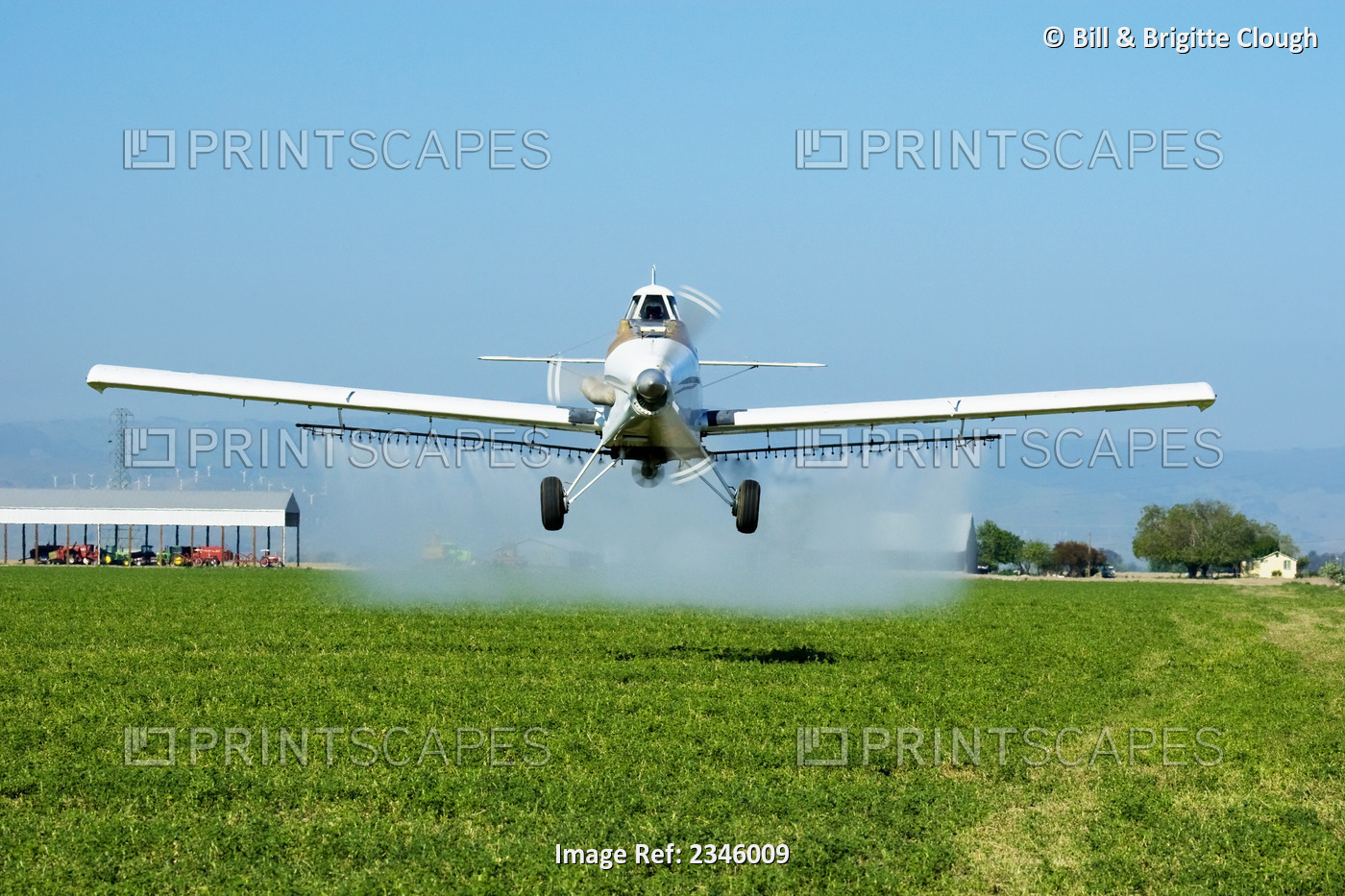 Agriculture - White crop duster flying low while spraying an alfalfa field / ...