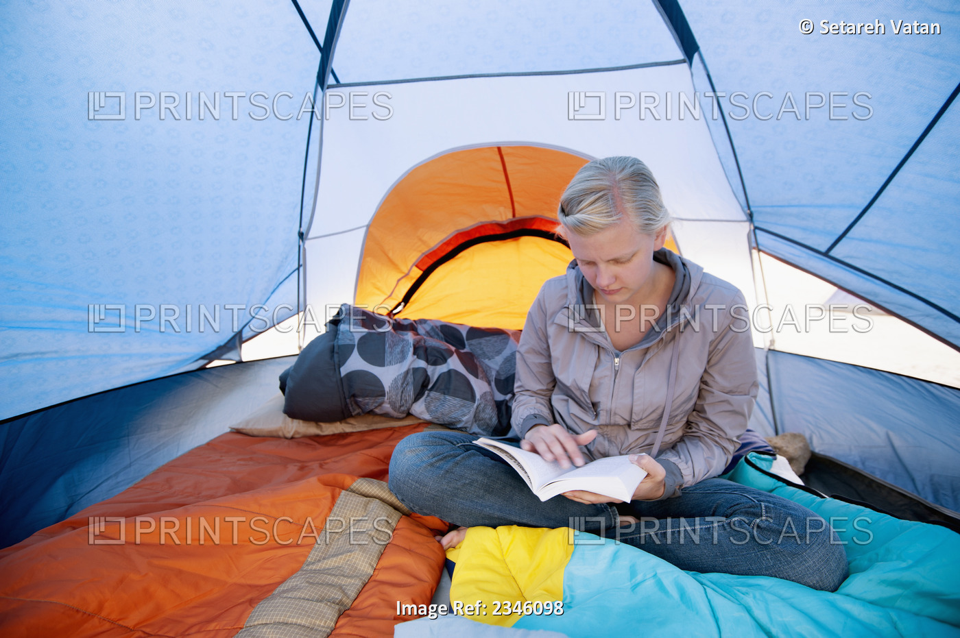 A Young Woman Reading A Book Inside A Tent; California, United States Of America