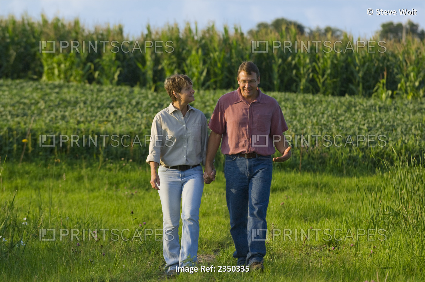 Agriculture - Husband and wife farmers walk hand-in-hand with their grain corn ...