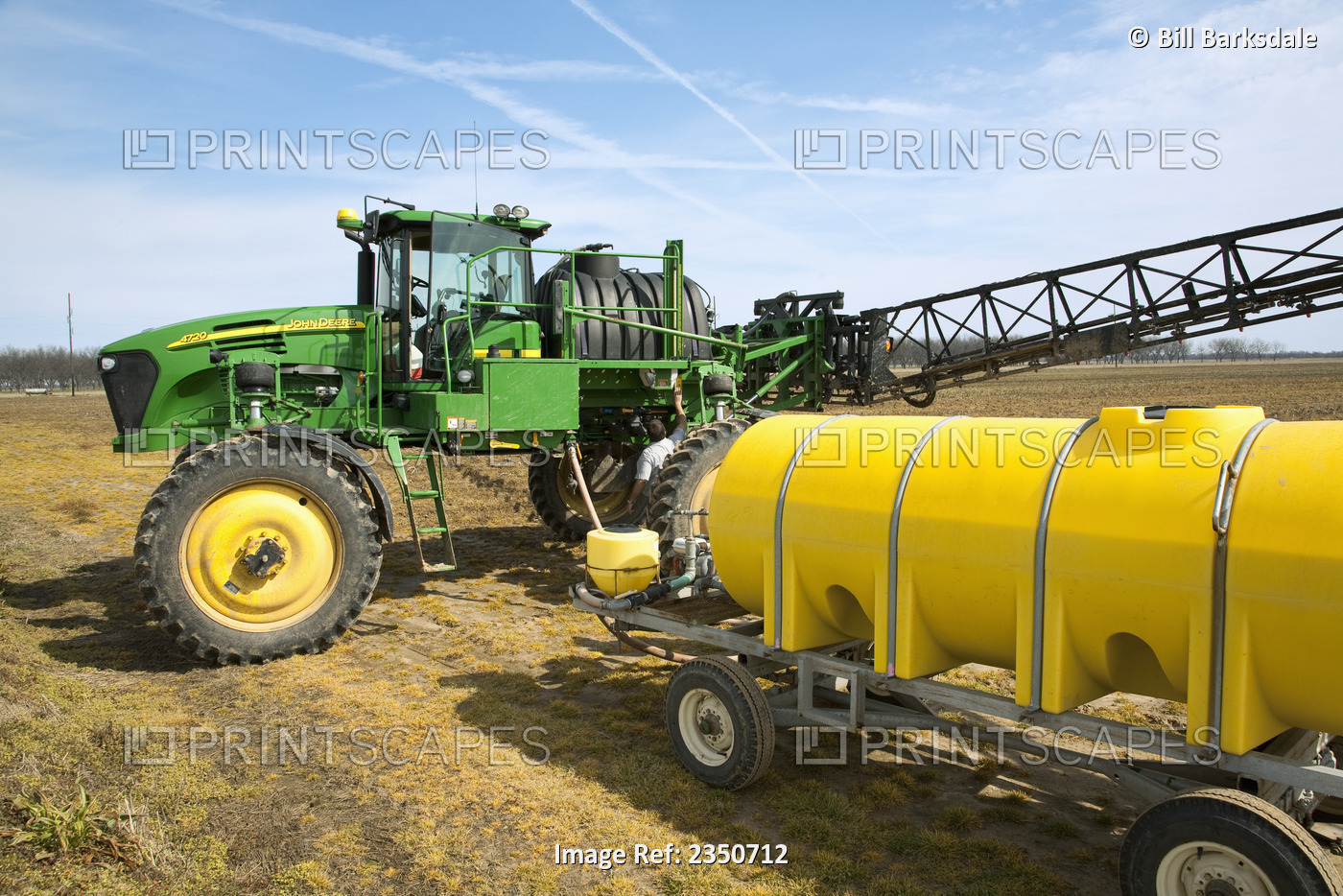 Agriculture - A farmer refills the chemical tank of his John Deere sprayer in ...
