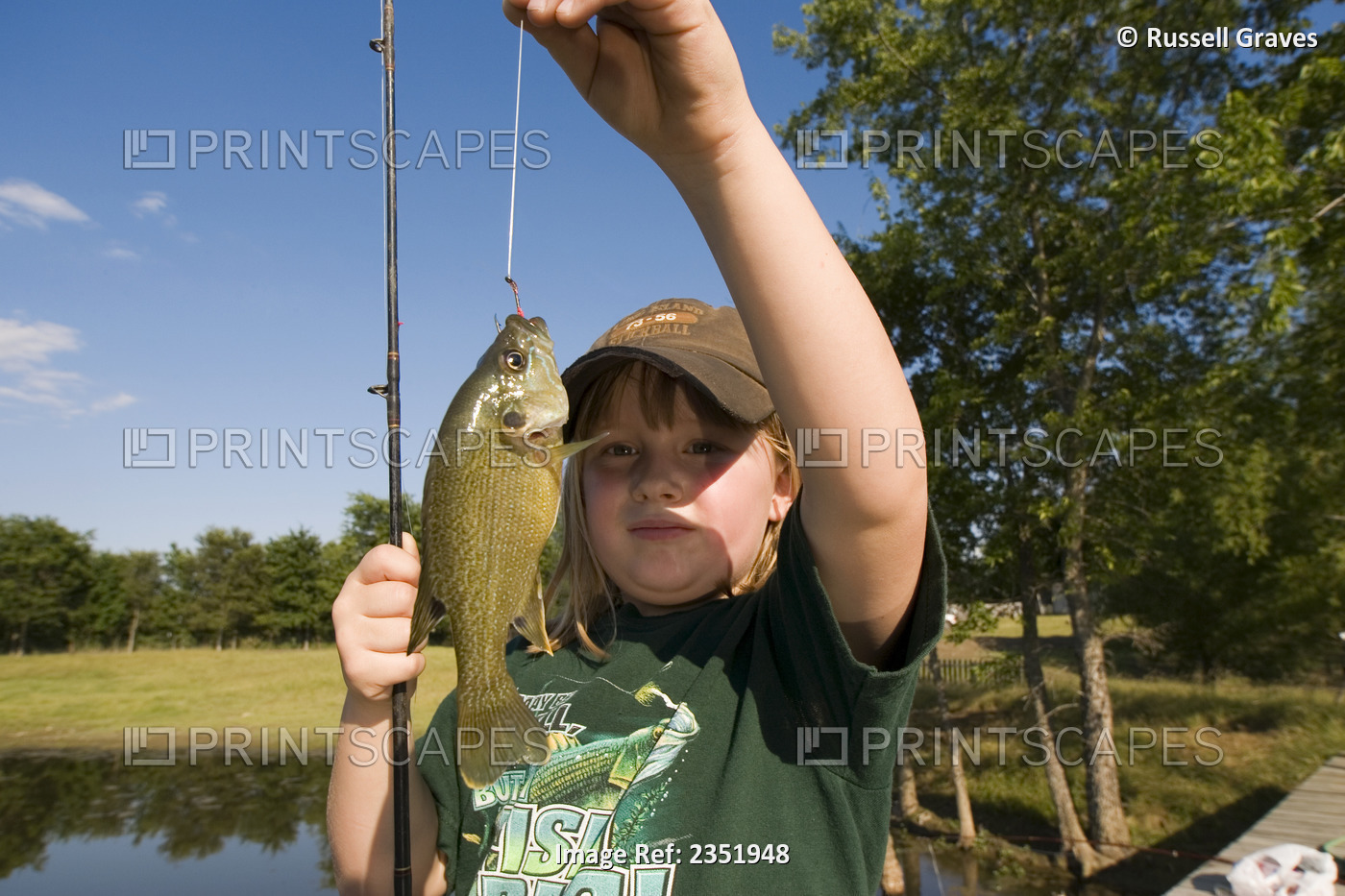 Agriculture - A farm girl holds up a blue gill sunfish she just caught from a ...