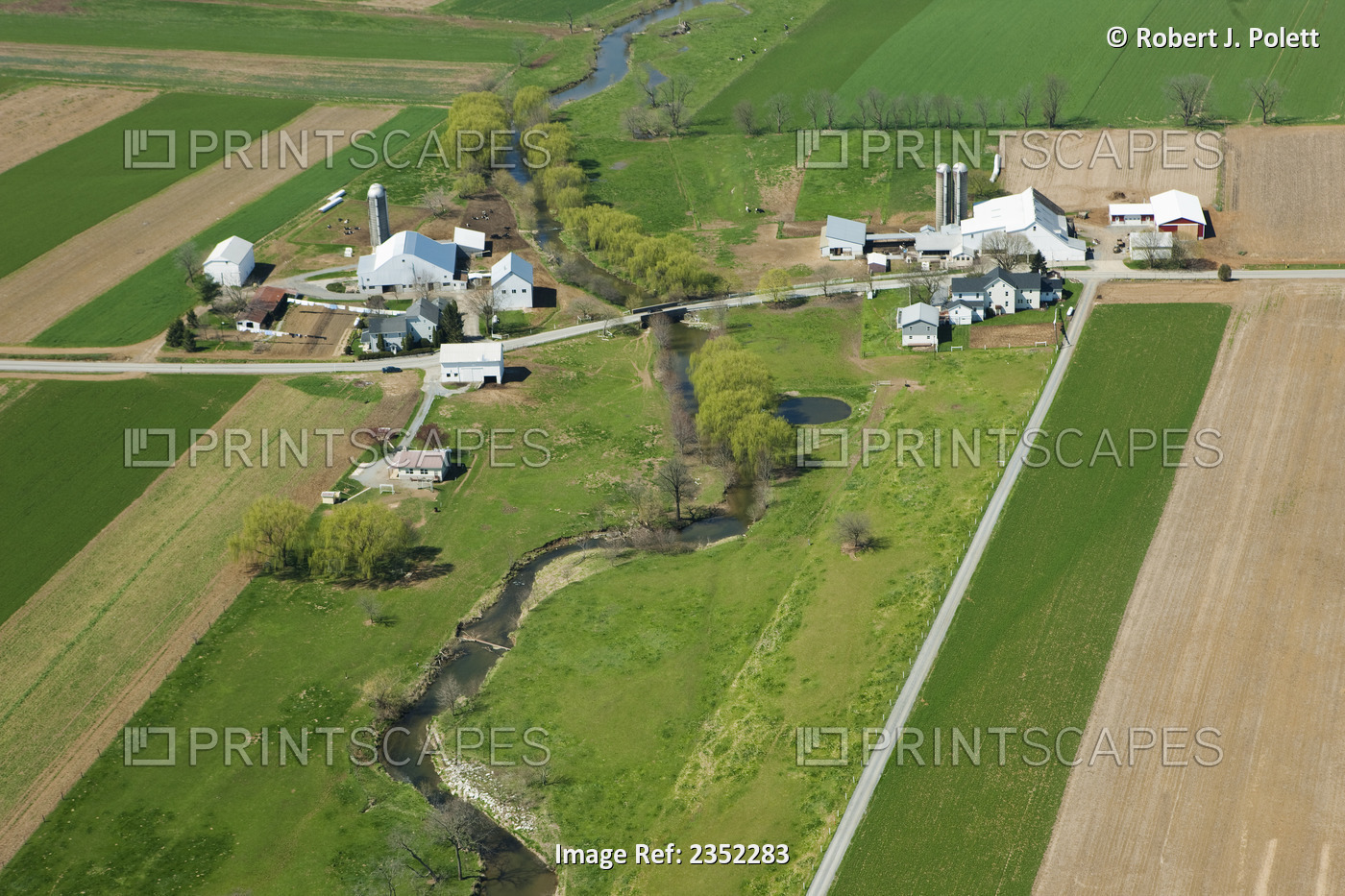 Agriculture - Aerial view of farmsteads, agricultural fields and a creek in mid ...
