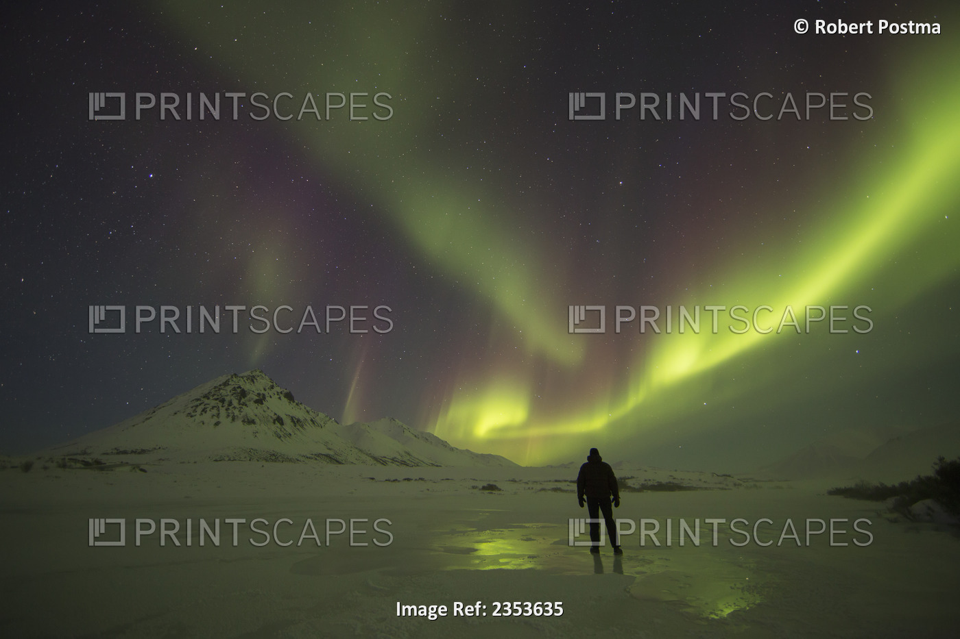 A Person Stands On The Frozen Blackstone River Beneath The Northern Lights; ...