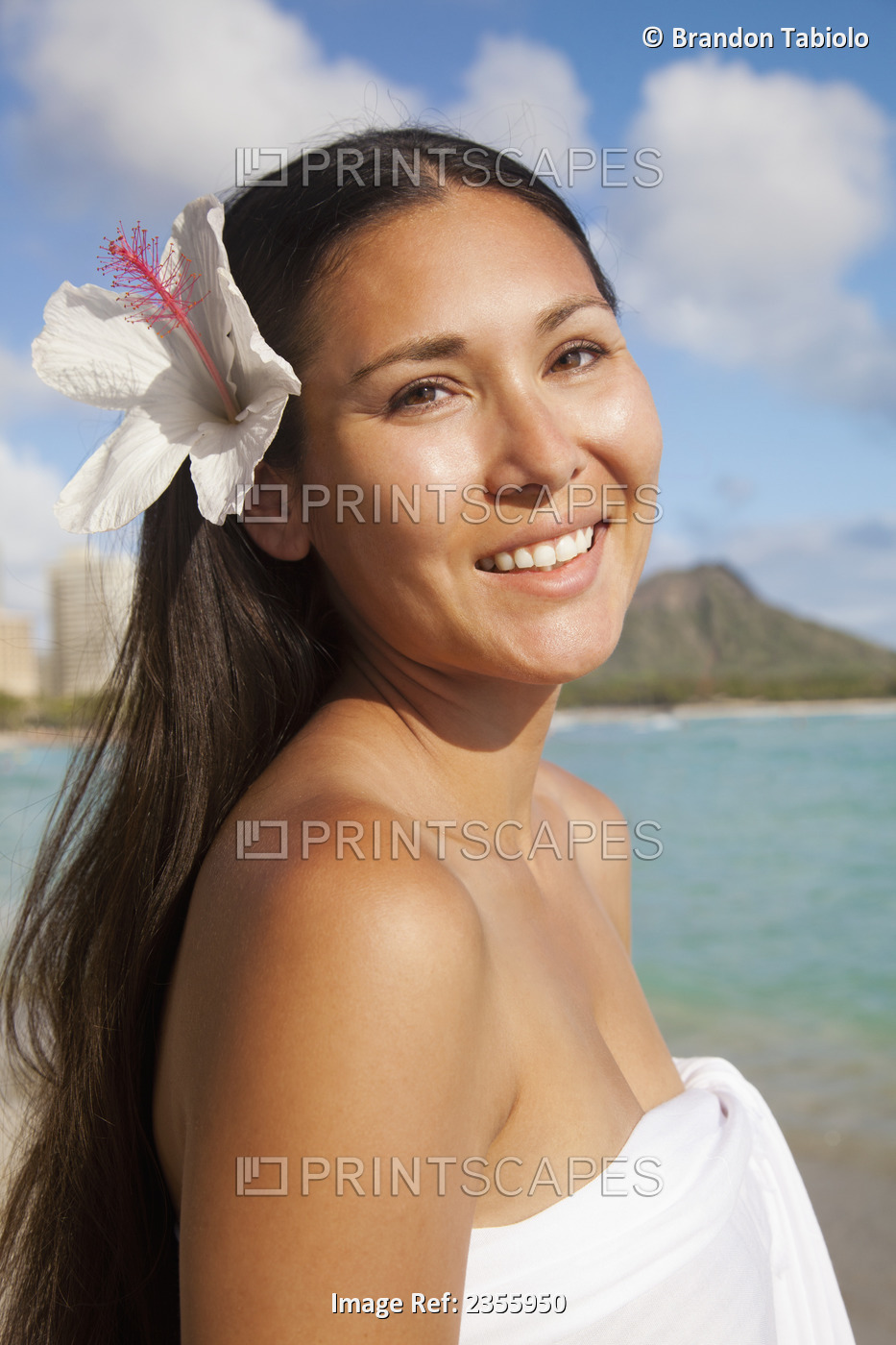 A Young Woman Poses On A Beach With A Hibiscus Flower In Her Hair; Waikiki, ...