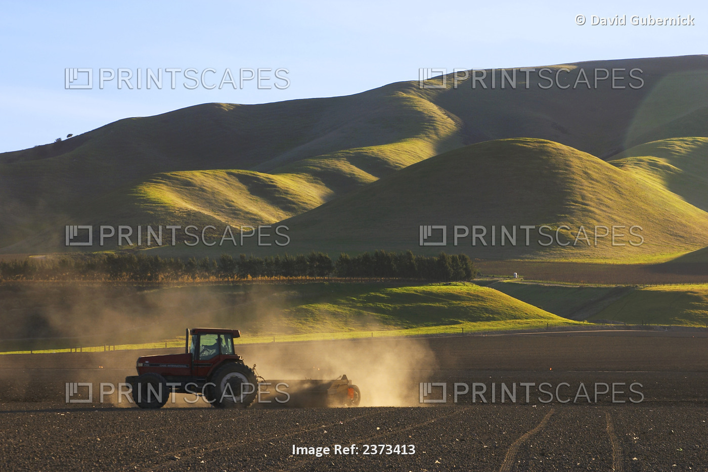 Agriculture - A tractor pulls a land leveler across a field in order to level ...