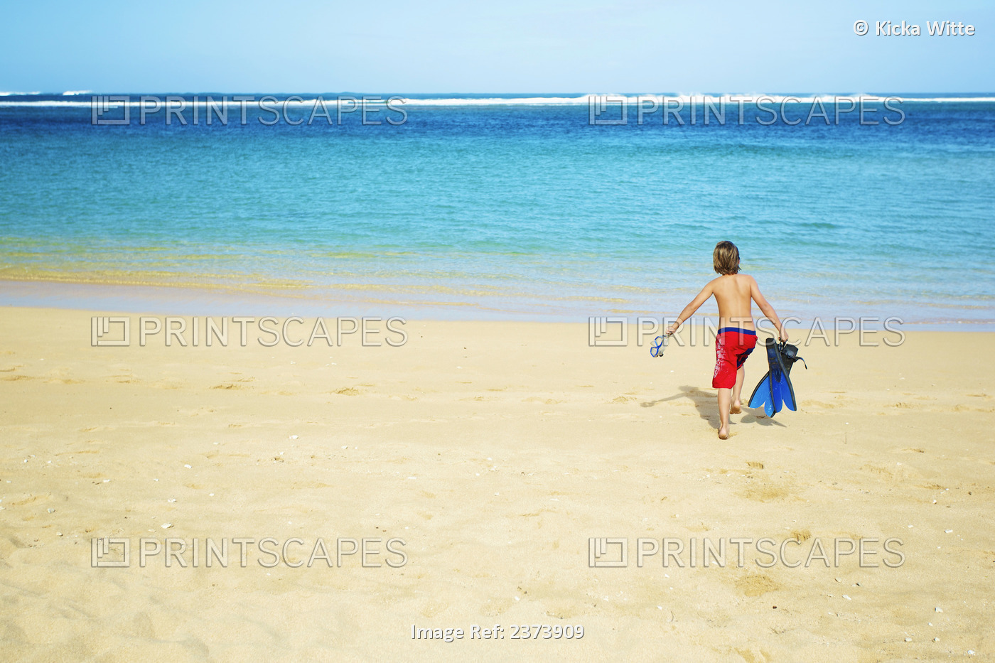 A Boy Running Out To The Ocean Across The Beach With Snorkelling Gear; Kauai, ...