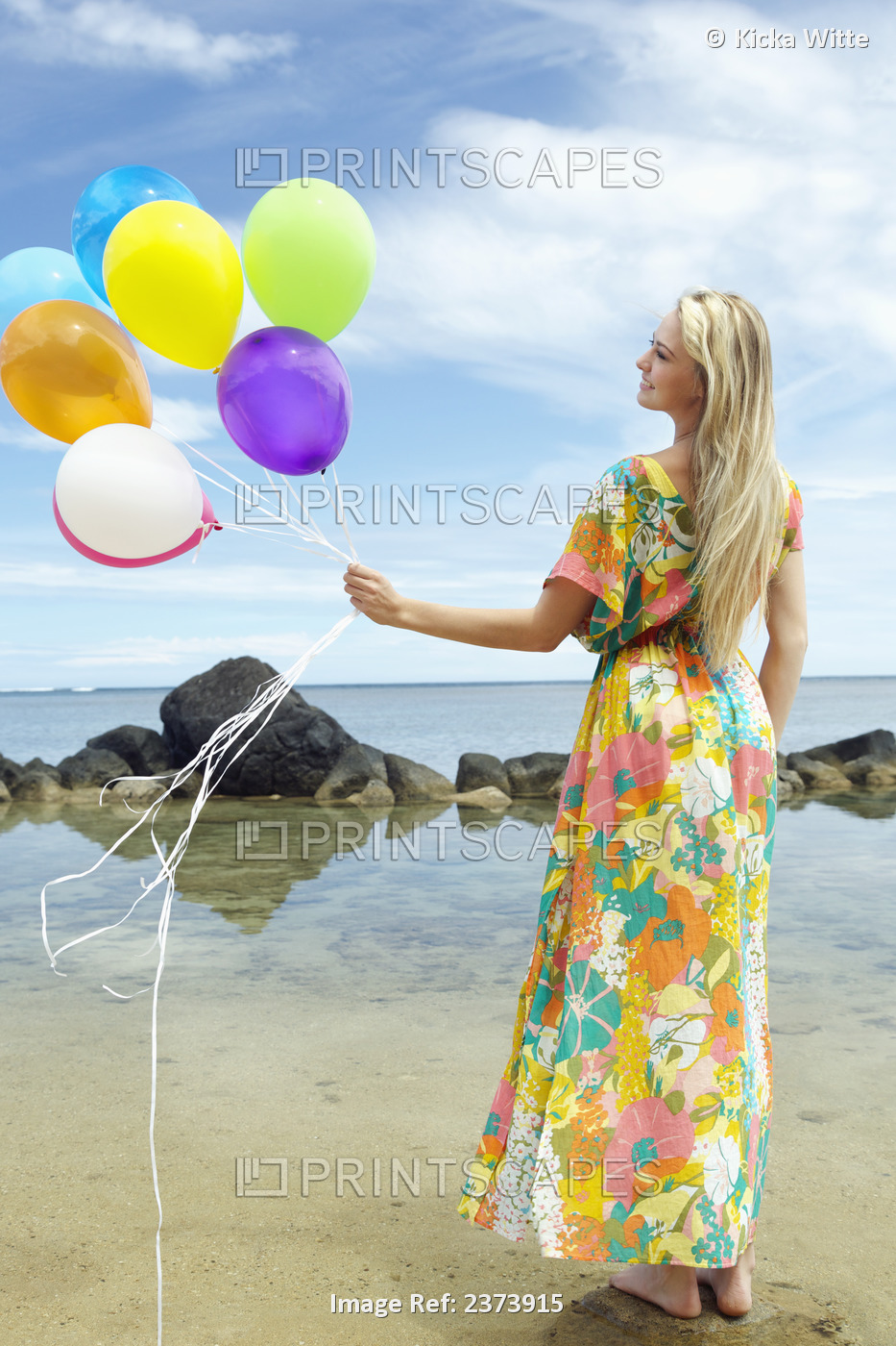A Young Woman In A Floral Dress Standing On The Beach Holding A Bundle Of ...