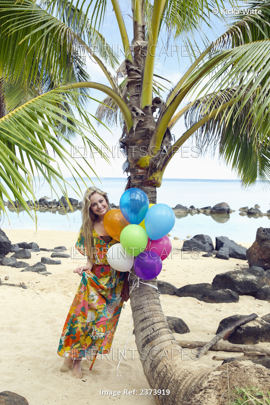 A Young Woman In A Floral Dress Holding A Bundle Of Colourful Balloons On The ...