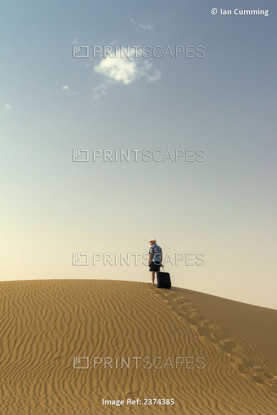 Barefoot Man With Suitcase On Sand Dune; Dubai, United Arab Emirates