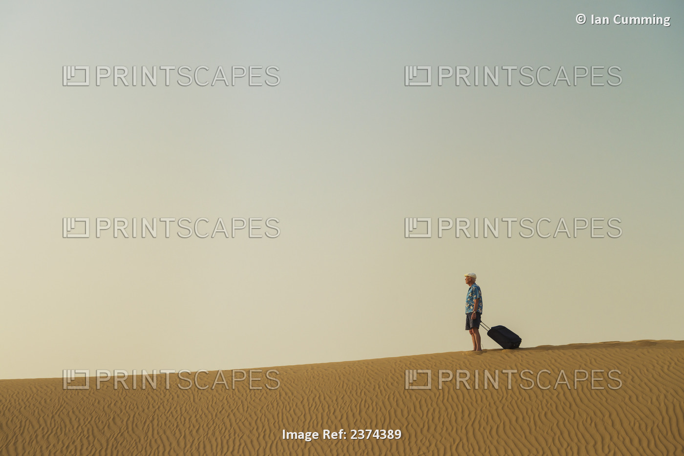 Barefoot Man With Suitcase On Sand Dune; Dubai, United Arab Emirates