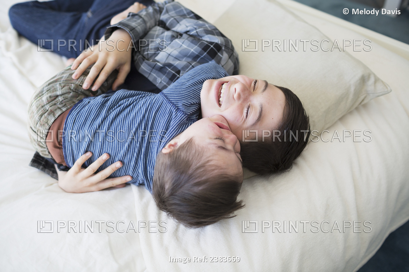 Brothers Playing On A Big Bed At Home, One Young Boy Has Down syndrome; ...