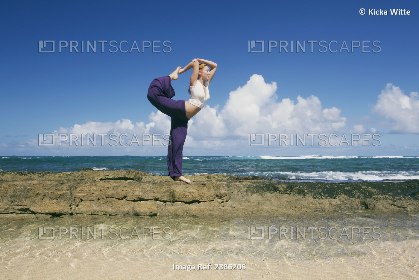 A Young Woman Does A Yoga Pose On A Rock Wall At The Water's Edge; Kauai, ...
