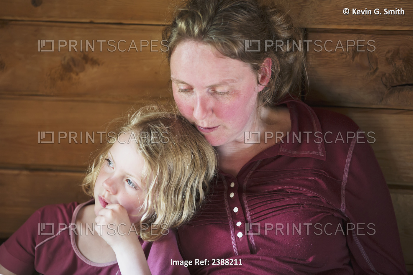 A Mother And Daughter Sitting Together Reading A Book, Leaning Against A Wooden ...