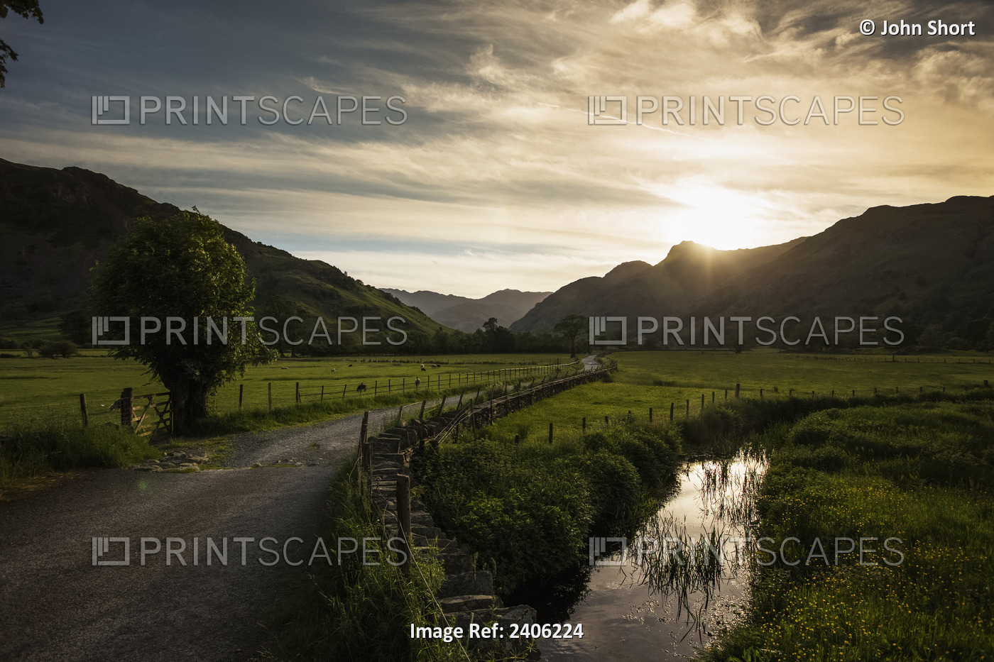 A Gravel Road Between Fields As The Sun Sets Behind The Mountains; Lake ...