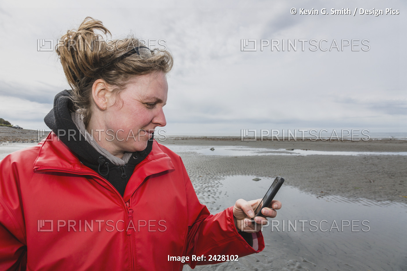 Woman Using Her Smart Phone While Walking On Point Beach, Anchor Point, ...