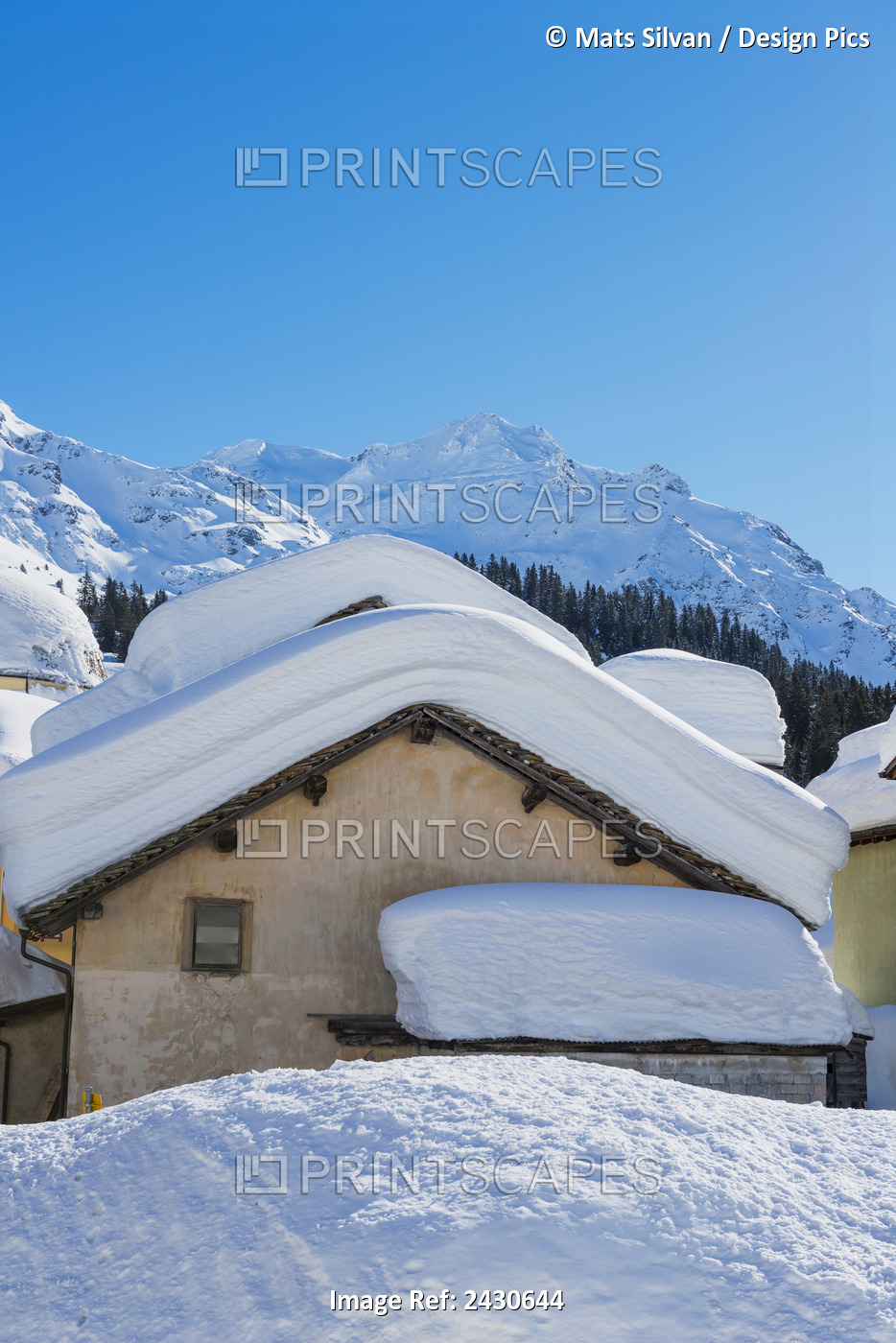 Snow Covered Roofs Of Houses With Rugged Snow Covered Mountains In The ...