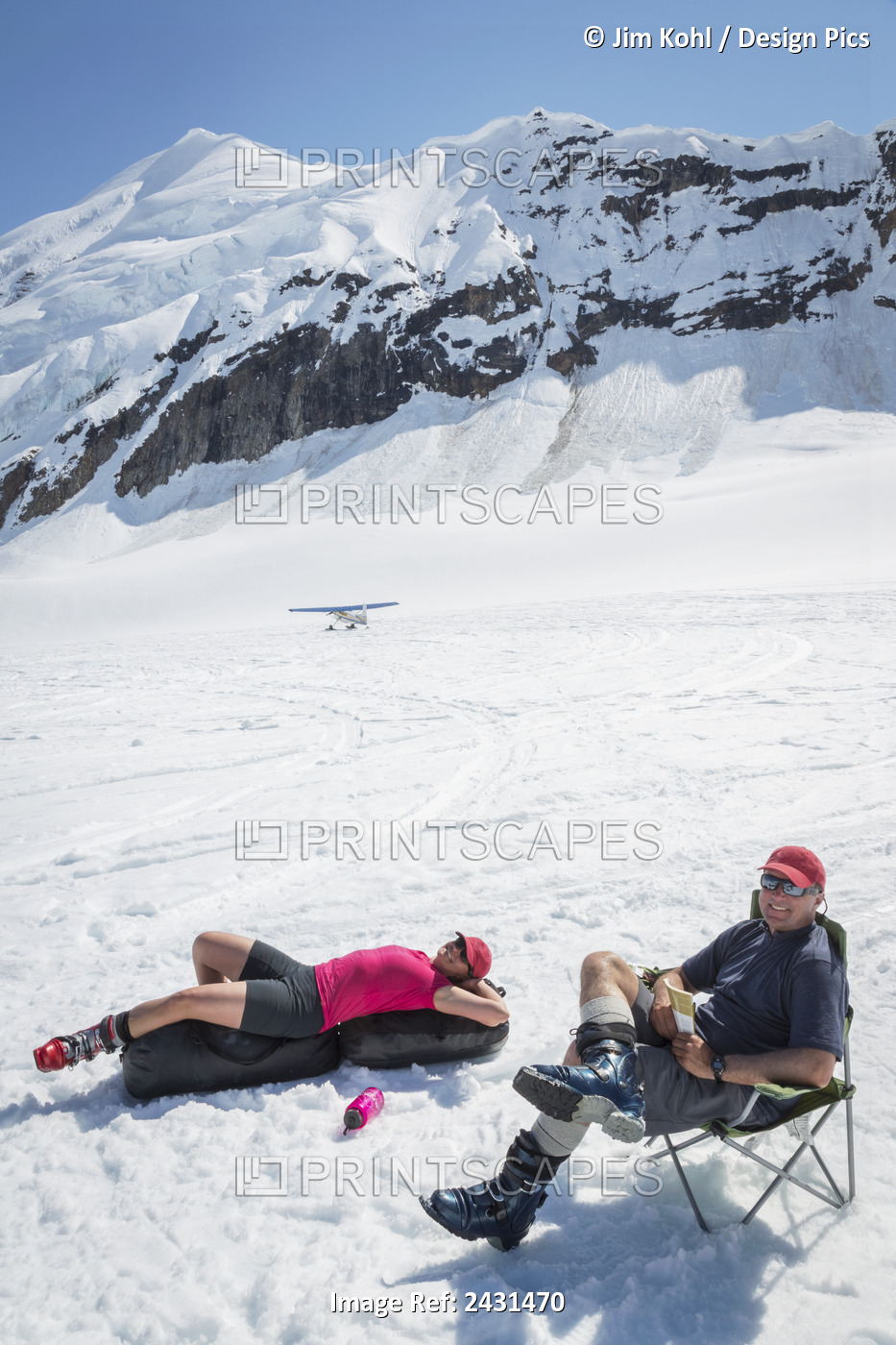 A Couple Relaxes While Awaiting A Ski Plane Pick Up On The Ruth Glacier In The ...