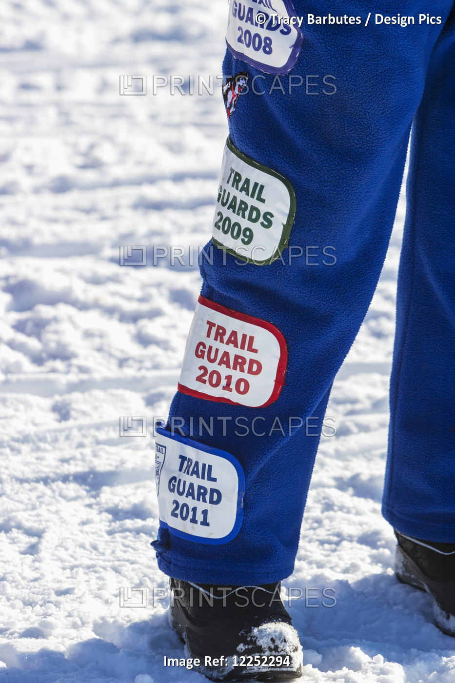 Close Up Of A Volunteer's Leg Covered In Patches From Previous Iditarod Races, ...