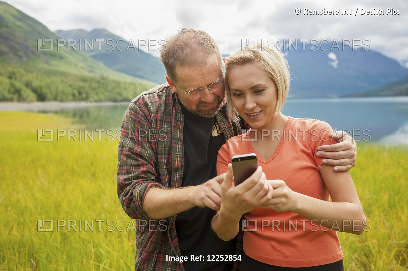Man And Woman Reviewing Photos On A Smartphone In Front Of Eklutna Lake, ...