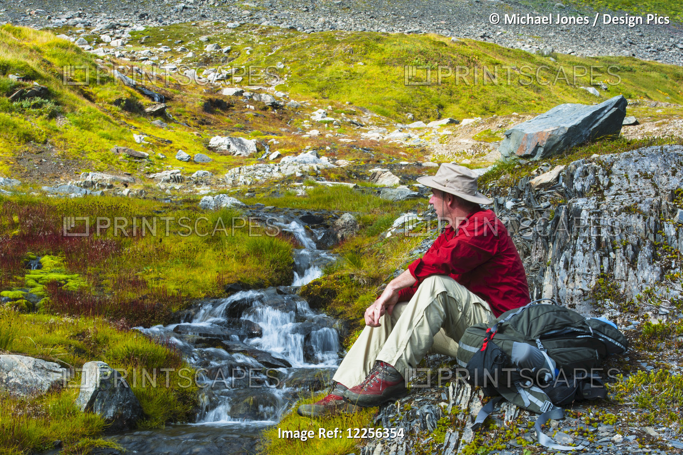 A Man Sitting Next To A Stream, Kenai Fjords National Park, Kenai Penninsula, ...