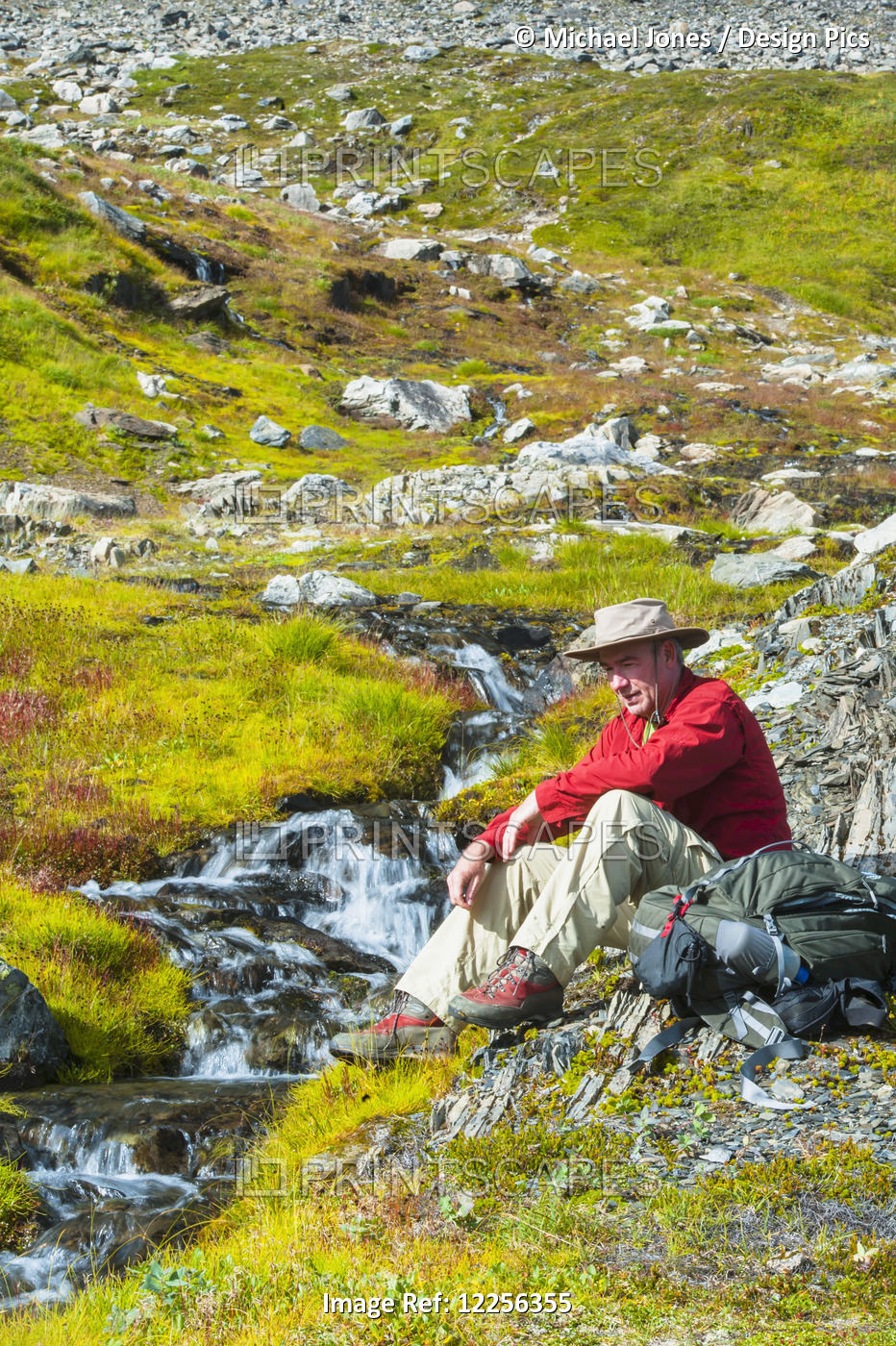A Man Sitting Next To A Stream, Kenai Fjords National Park, Kenai Penninsula, ...