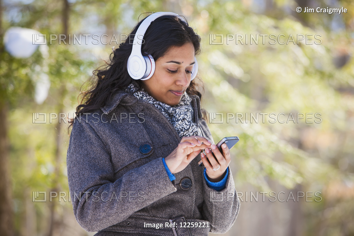 Young Woman Of South Asian Ethnicity Using Cell Phone And Bluetooth Headphones ...